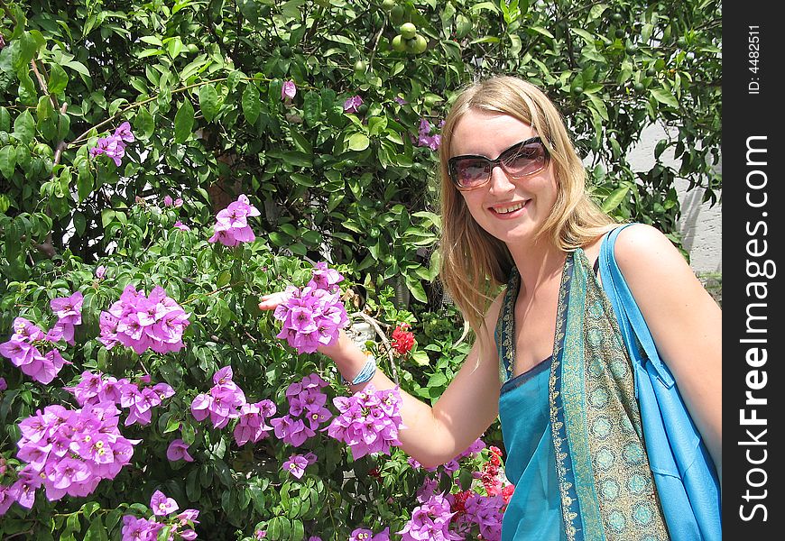 The beautiful girl is smelling flowers of bougainvillea. The beautiful girl is smelling flowers of bougainvillea