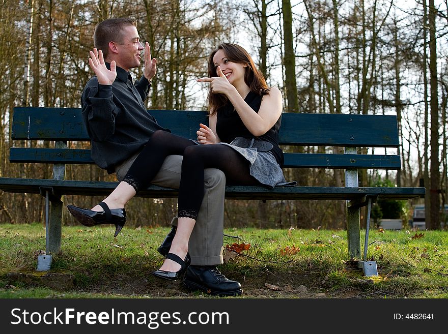 Man and girlfriend on a bench in a park having fun. Man and girlfriend on a bench in a park having fun