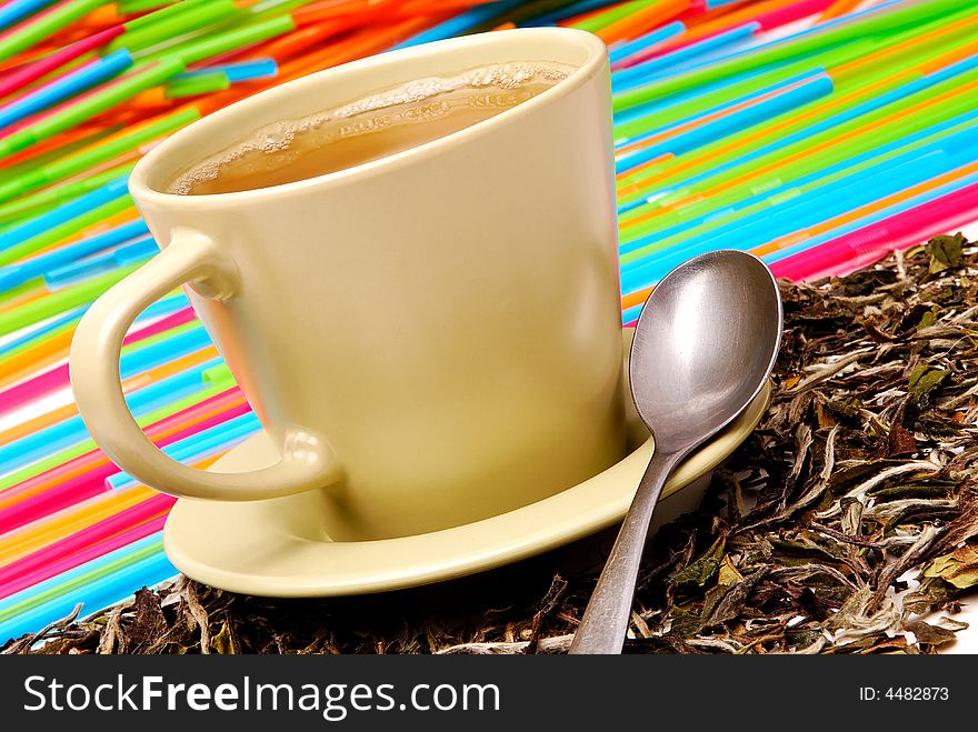 Cup of the green tea with spoon and leaves of tea around