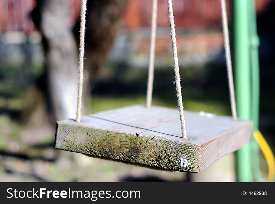 A solitary swinging chair in a solitary park.