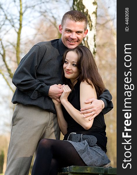 Man and girlfriend on a bench in a park caring. Man and girlfriend on a bench in a park caring