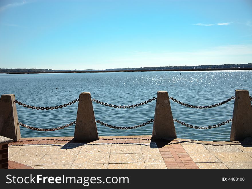 A chained fence wall on the edge of a boardwalk overlooking the ocean. A chained fence wall on the edge of a boardwalk overlooking the ocean.