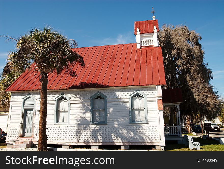 An old church building downtown with spanish moss growing off a nearby tree.