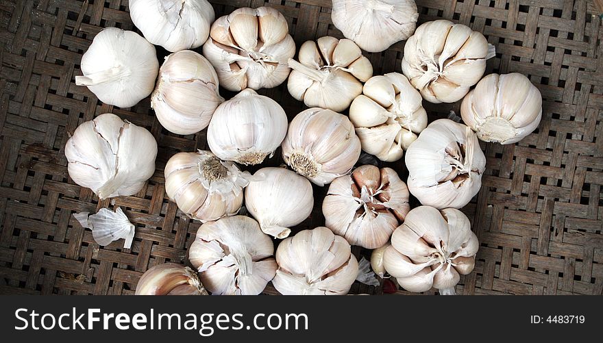 Whole cloves of garlic in a woven cane basket.