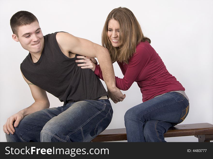 Young couple sitting on a bench wrestling. Young couple sitting on a bench wrestling