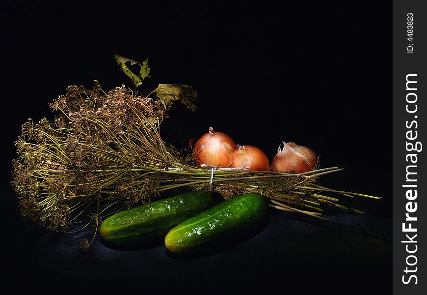 A punch of dill, two cucumbers and tree onions lying on the black background. A punch of dill, two cucumbers and tree onions lying on the black background