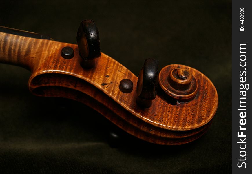 Close-up of violin scroll and pegbox, with part of neck... on dark green velvet. Close-up of violin scroll and pegbox, with part of neck... on dark green velvet