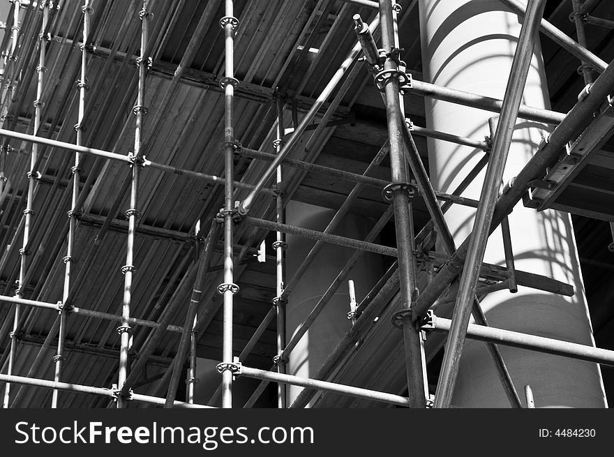 Restoration construction on a public building with shadowed scaffolding and an illuminated column. Restoration construction on a public building with shadowed scaffolding and an illuminated column