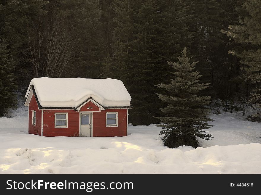 Heavy winter snow covering old red house in forrest. Heavy winter snow covering old red house in forrest