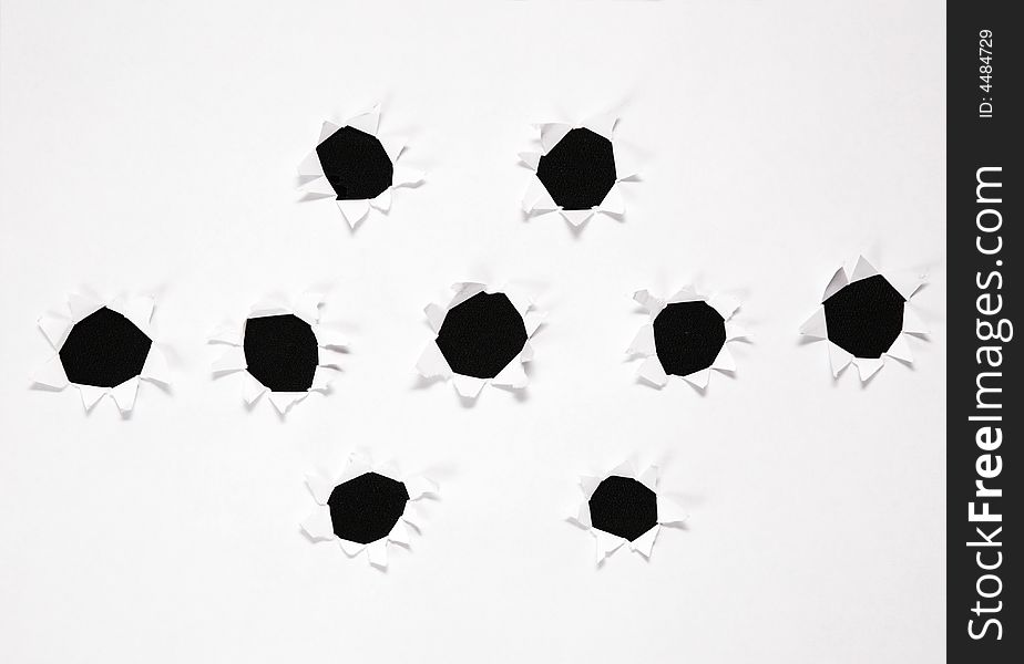 The sheet of paper with the group of holes against the black background