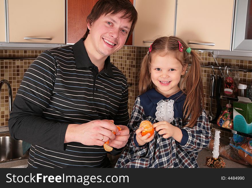 Father And Daughter With Mandarins On Kitchen