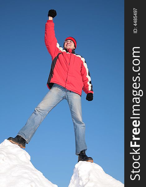 Man in red jacket on top of snow hill with hand up