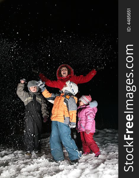 Children and mother throw snow in night