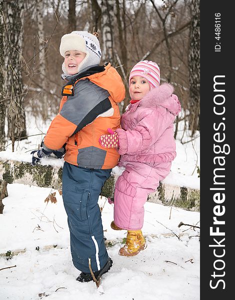 Boy and girl sit on fallen tree