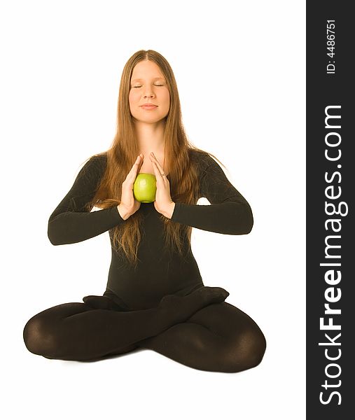 The portrait of a woman in lotus pose with a green apple in her hands. The portrait of a woman in lotus pose with a green apple in her hands