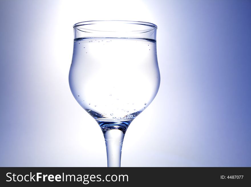 Nice goblet with light drink and blebs standing on white-blue background. Nice goblet with light drink and blebs standing on white-blue background