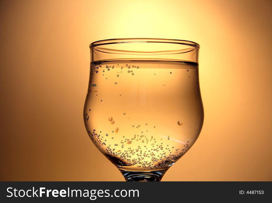 Nice goblet of champagne with blebs standing on golden background. Nice goblet of champagne with blebs standing on golden background