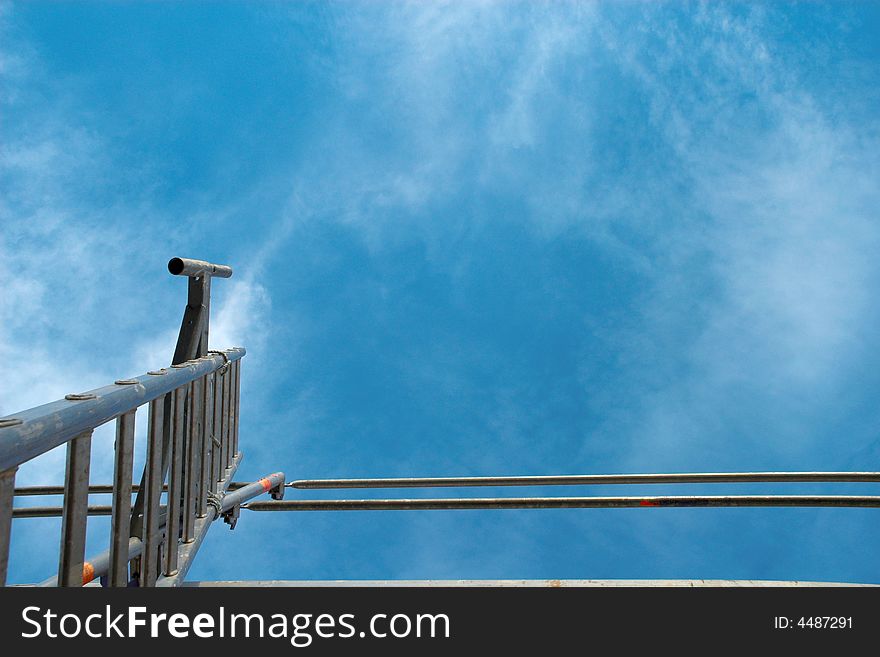 Ladder at a scaffold against the blue sky. Ladder at a scaffold against the blue sky.