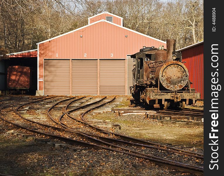 Old rusted locomotive on tracks outside depot