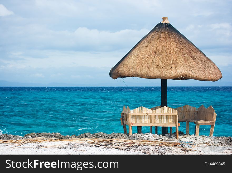 Relaxing native style cabanas on a white sand tropical beach beside the ocean of Caribbean blue water with white foamy waves crashing. Relaxing native style cabanas on a white sand tropical beach beside the ocean of Caribbean blue water with white foamy waves crashing
