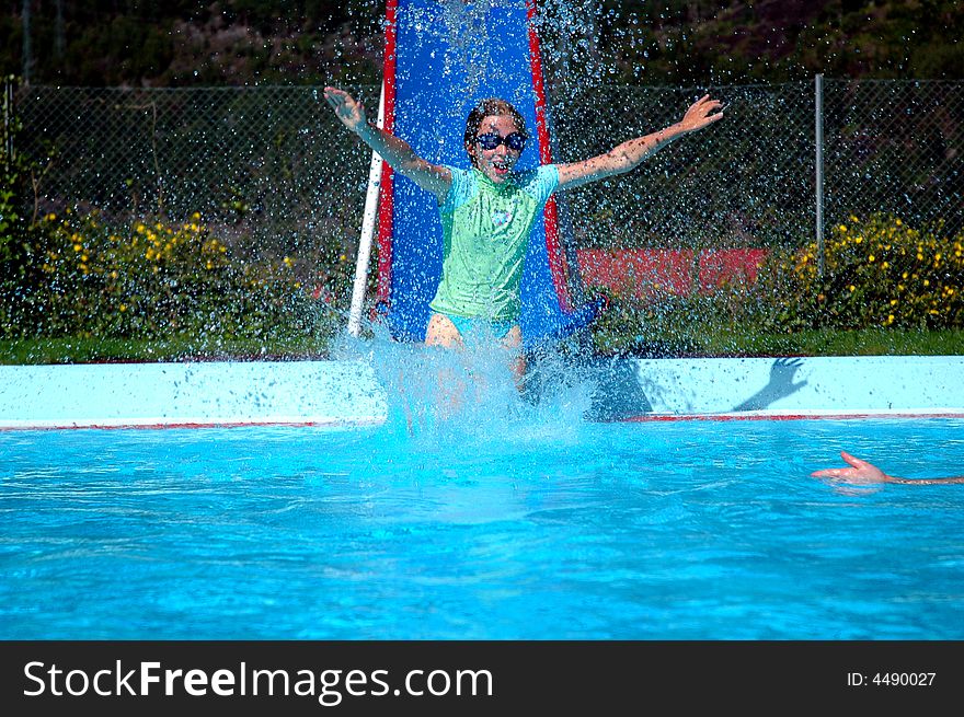 Girl going down slide into swimming pool