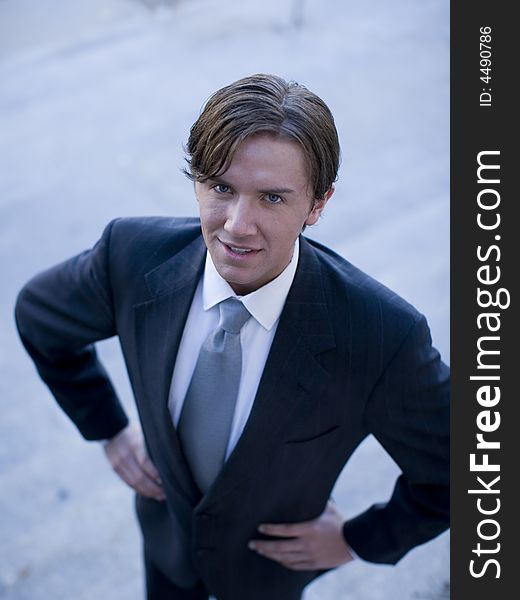 High-angle view of young white businessman standing wearing suit looking up at cameraman. High-angle view of young white businessman standing wearing suit looking up at cameraman