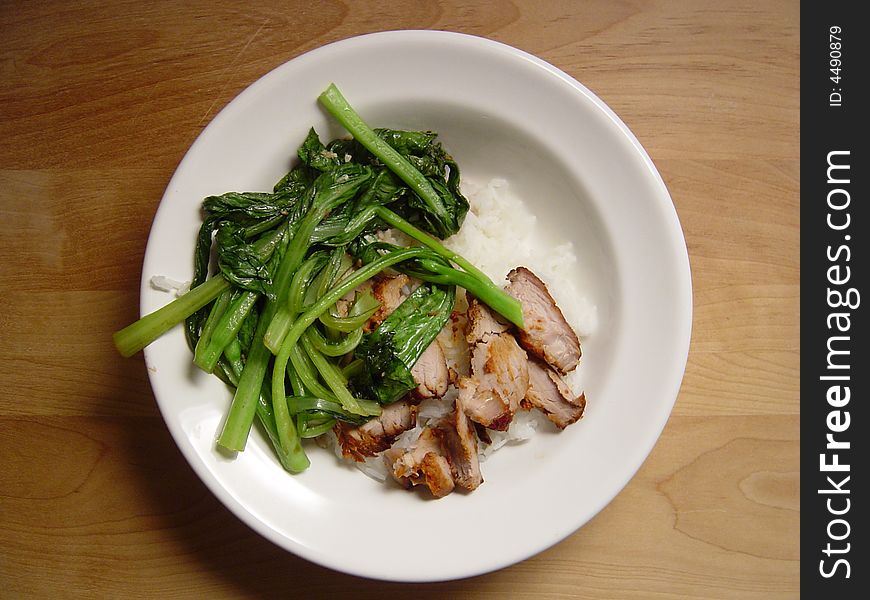 Char Siu pork and rice dish on a wood table.