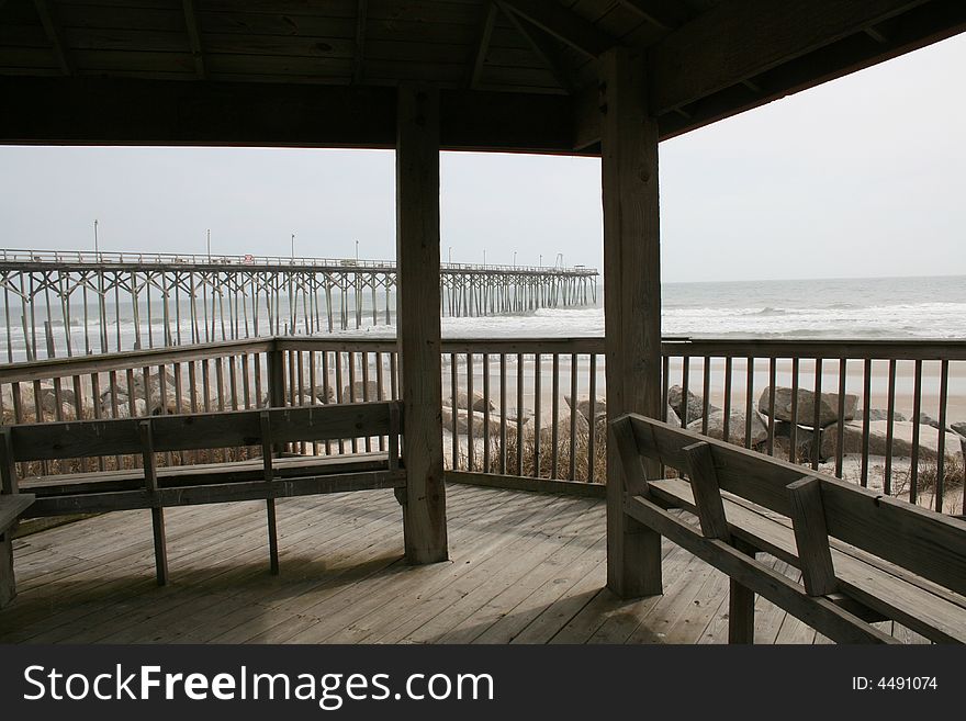 Covered deck seating at the beach with a view of the ocean and pier. Covered deck seating at the beach with a view of the ocean and pier.