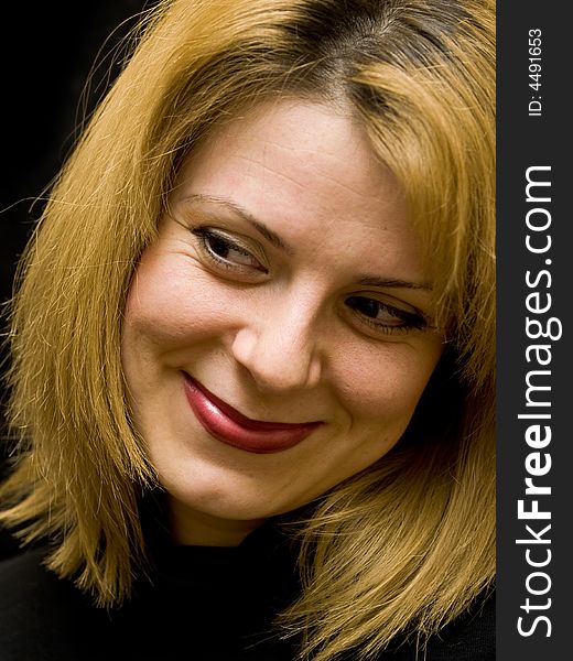 Woman looking down on black background smiling