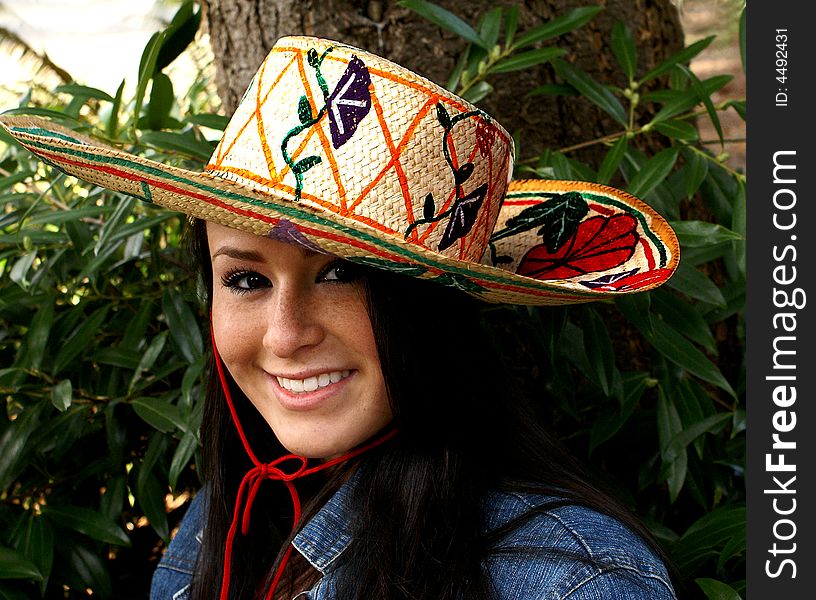 Teenager in outdoor setting wearing sombrero with gardening motif. Teenager in outdoor setting wearing sombrero with gardening motif