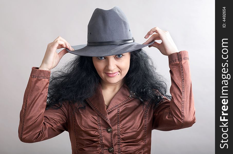 A beautiful girl holding her grey hat. A beautiful girl holding her grey hat