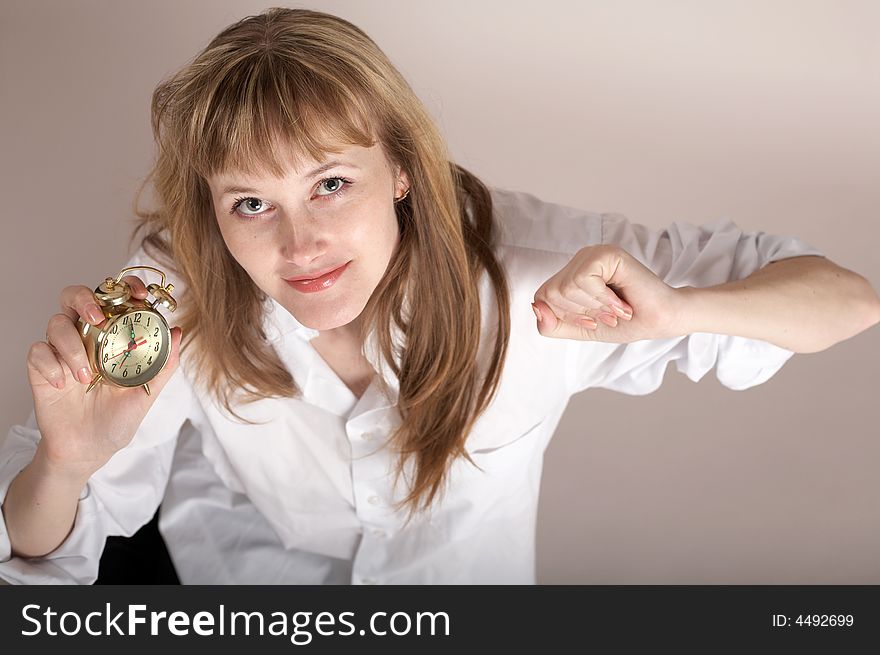 A nice girl in a white shirt holding an alarm-clock. A nice girl in a white shirt holding an alarm-clock