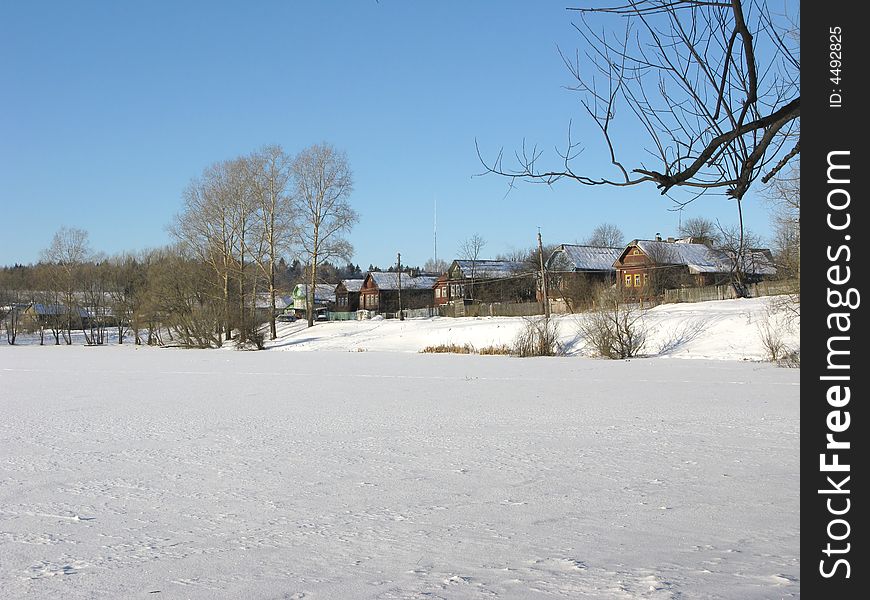 Frozen lake, small village, sunny winter day. Frozen lake, small village, sunny winter day