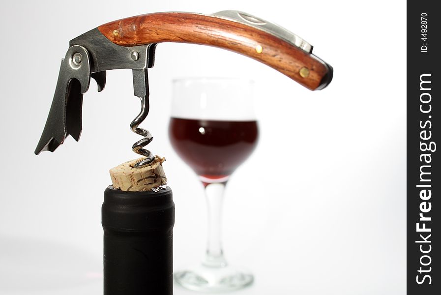 Black bottleneck with cork and nice corkscrew on background with wineglass. Black bottleneck with cork and nice corkscrew on background with wineglass