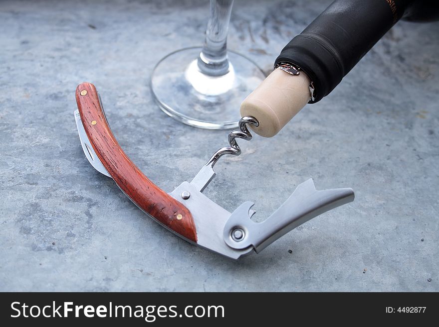 Black bottleneck with cork and nice corkscrew on background with wineglass. Black bottleneck with cork and nice corkscrew on background with wineglass