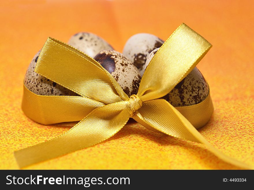 Quail eggs tied with yellow ribbon on orange background. Quail eggs tied with yellow ribbon on orange background