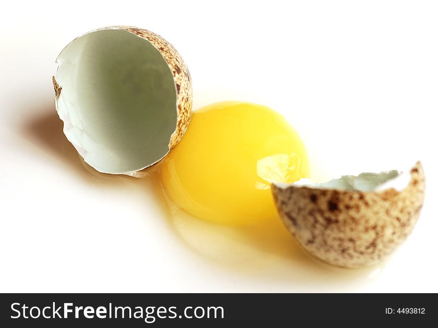 Raw quail egg and eggshell on white background