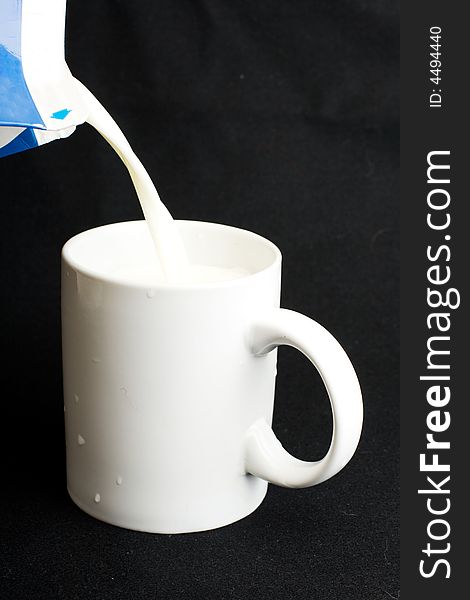 Milk flowing from packet to the mug. Milk flowing from packet to the mug