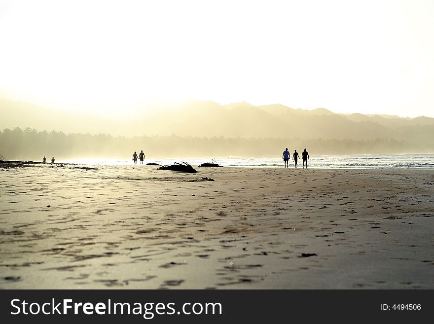 People walking on the beach by beautiful tropical sunset. People walking on the beach by beautiful tropical sunset