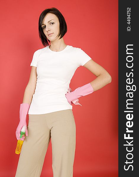 Young woman in pink rubber gloves holding in hands washcloth and bottle of cleanser. Looking at camera, front view. Young woman in pink rubber gloves holding in hands washcloth and bottle of cleanser. Looking at camera, front view.