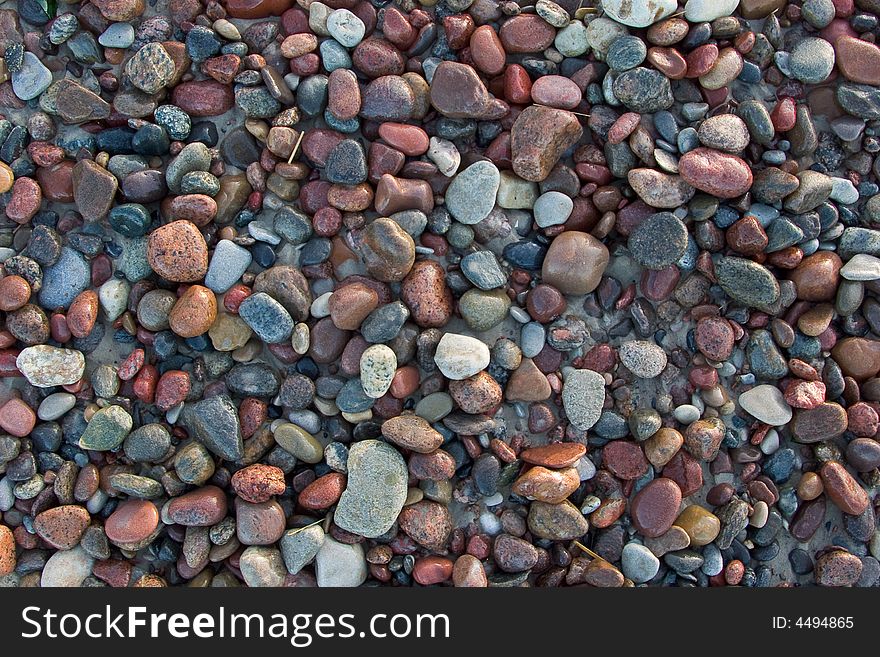 Wet sunlit beach pebbles background