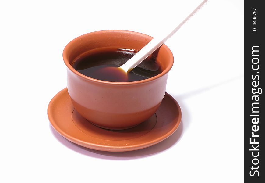 A small cup of coffee on a white background with a disposable spoon