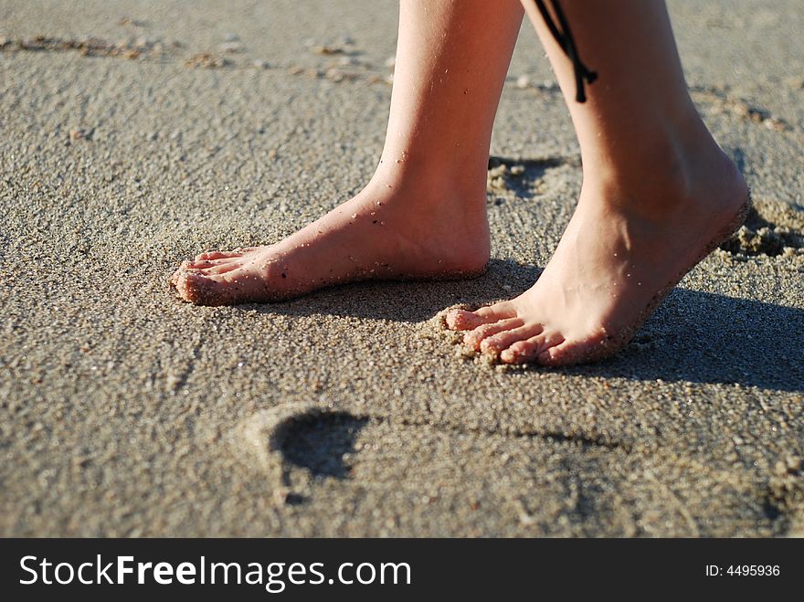 Girl's bare foot is on the beach. Girl's bare foot is on the beach