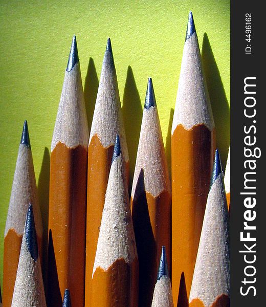 Stack of sharpened pencils against yellow background.