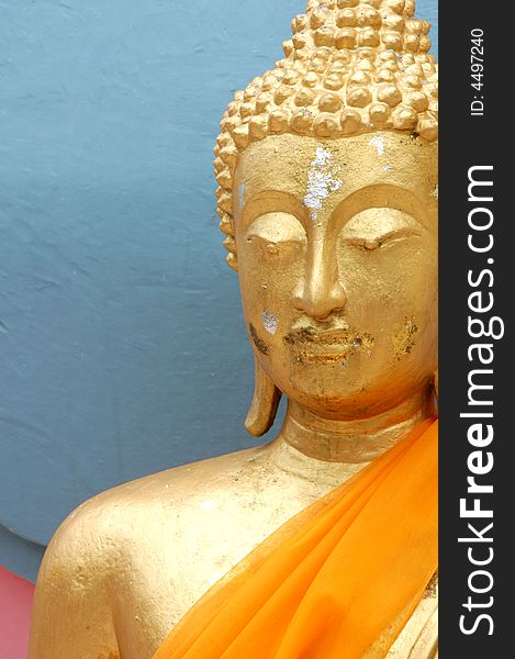 Gold buddha statue from Puckett Thailand with orange scarf and erosion around the face and body