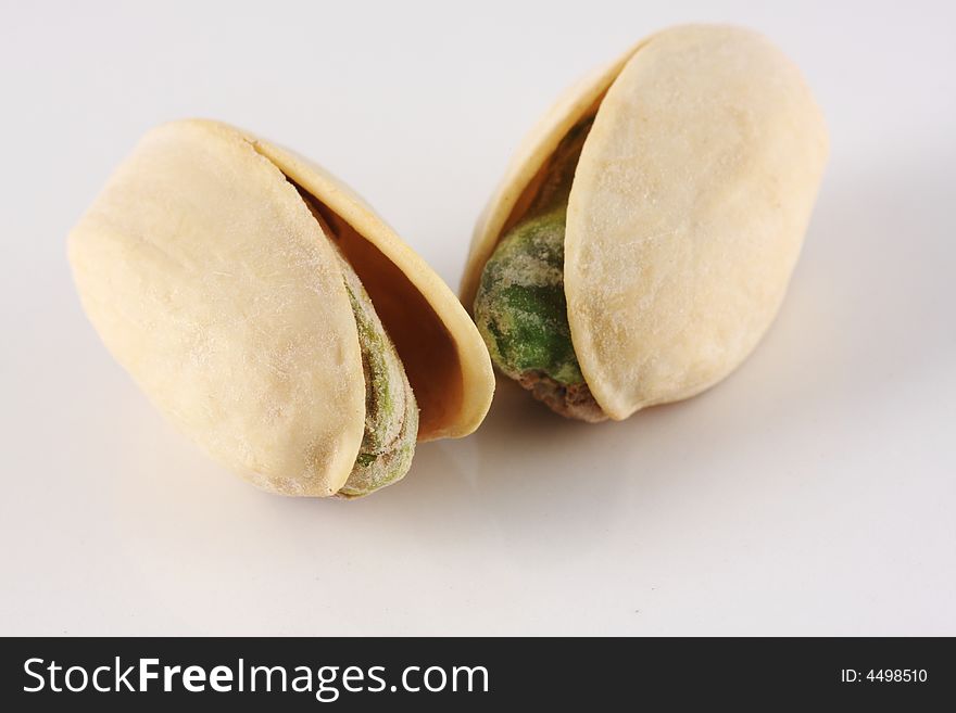 Two pistachio nuts seen up close on a white background.