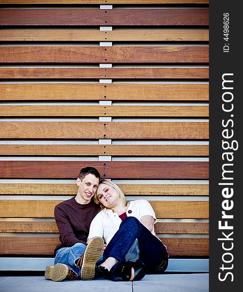 Young couple cuddling in front of a wall made of wood slats. Young couple cuddling in front of a wall made of wood slats