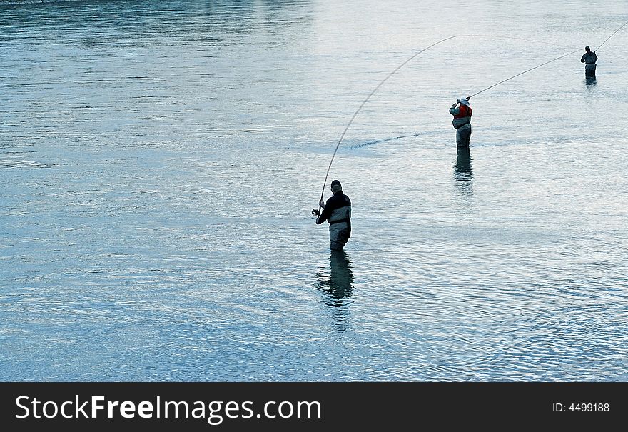 3 fishermen silhouetted against the river