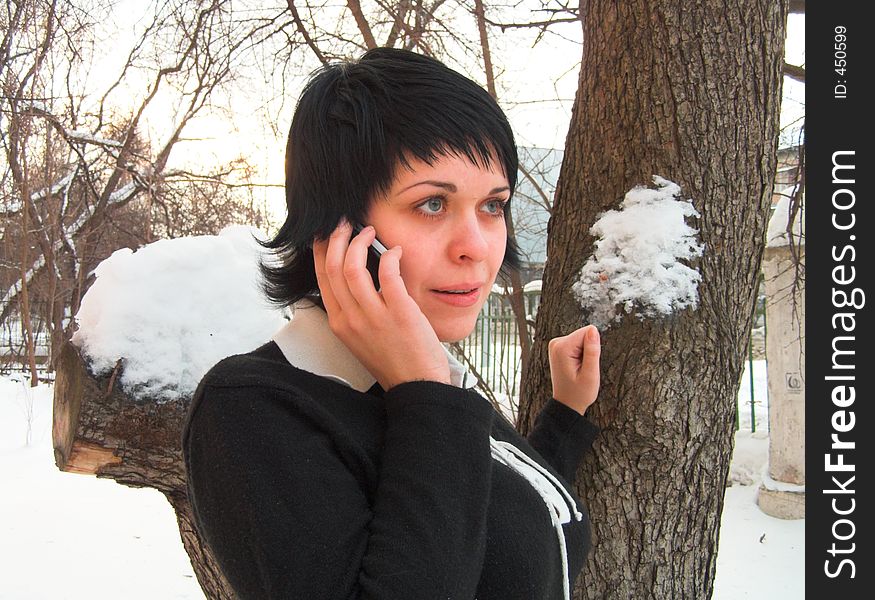 The woman speaks by phone in the winter. The woman speaks by phone in the winter