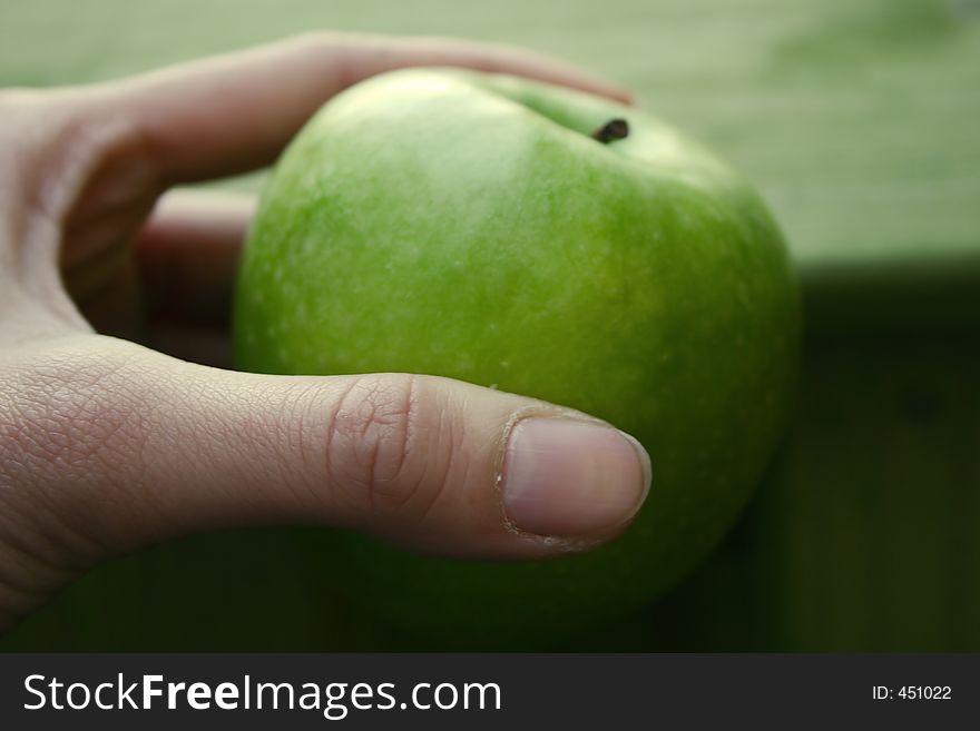 Hand holding a green apple